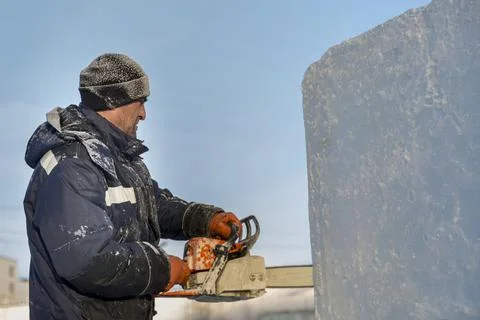Worker cuts ice panel with gasoline saw 스톡 사진