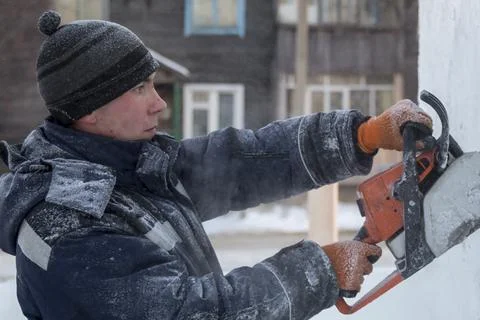 Worker cuts ice panel with gasoline saw 스톡 사진