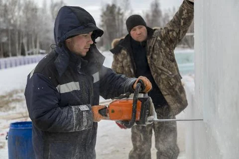 Worker cuts ice panel with gasoline saw Stock-Fotos