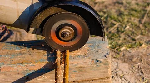 The worker cuts the metal with an angle grinder, the work is carried out on t Fotos de archivo