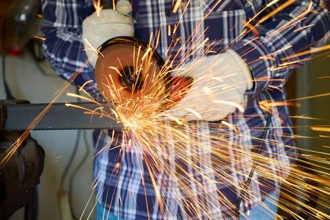 A worker cuts metal with an angle grinder 스톡 사진