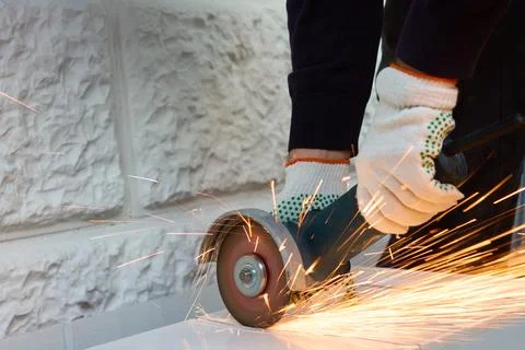 A worker cuts metal with an angle grinder Stock Photos