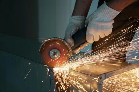 A worker cuts a metal part with an angle grinder Stock Photos
