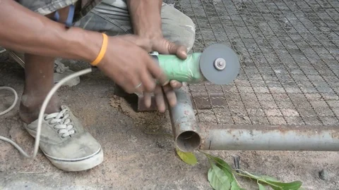 Worker cuts a metal pipe with some electric device or appliance Stock Footage 83784406