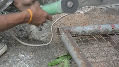 Worker cuts a metal pipe with some electric device or appliance Stock Footage 83784449