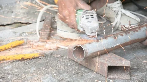Worker cuts a metal pipe with some electric device or appliance Stock Footage 83784632