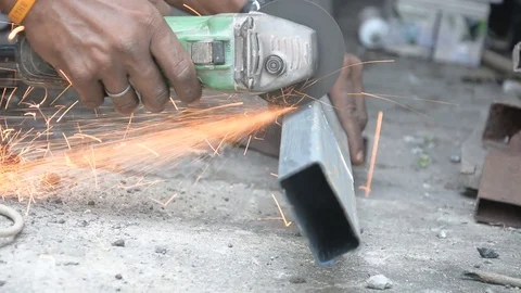 Worker cuts a metal pipe with some electric device or appliance Stock Footage 83787294