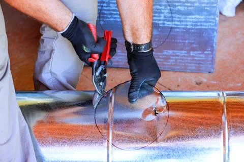 Worker cuts metal pipe in workshop using tools HVAC assemble Stock Photos