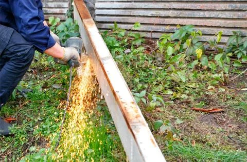 A worker cuts a metal structure using an angle grinder. Stock Photos