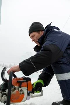 Worker cuts a niche under a chainsaw spotlight 写真素材