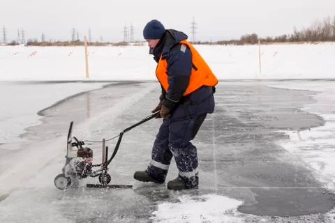 Worker cuts out ice blocks in size on the ice of a frozen lake 스톡 사진
