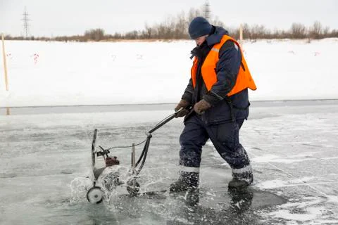 Worker cuts out ice blocks in size on the ice of a frozen lake 스톡 사진