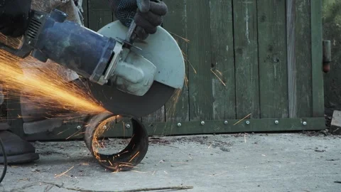 A worker cuts off a piece of pipe using an angle grinder. Siberia. Vídeos de archivo 241803002