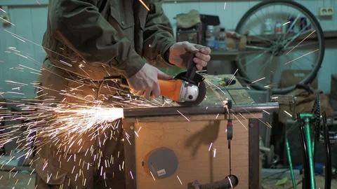 A worker cuts a pipe fixed by clamps on a worktable with an angle grinder. Stock-Footage 311759833