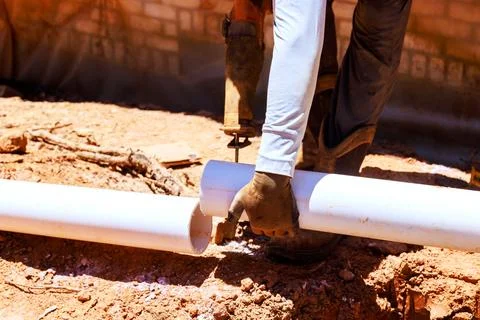 Worker cuts PVC pipe in construction site Stock Photos