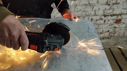 A worker cuts a sheet of iron with a grinder. Stock Footage 219227463