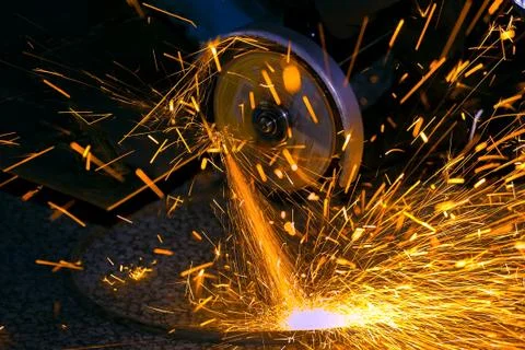 The worker cuts a sheet of metal with a grinder. Fly bright sparks. Working p