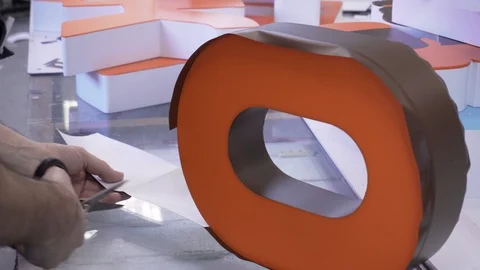 Worker cuts silver membrane on a volumetric letter 库存影片 128902664