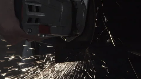 Worker cuts steel with angle grinder, sparks spraying downward Video stock 346253598