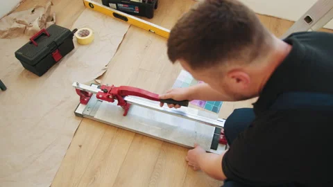 A worker cuts tiles with a tile cutter. Finishing work inside the premises Stock Footage 232160454