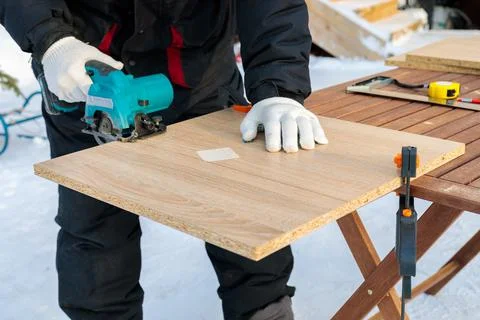 A worker cuts a wood panel with a circular saw. Stock Photos