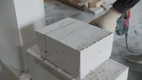 Worker cutting aerated concrete block with electric saw Stock Footage 306459866