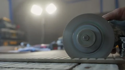 A worker is cutting a ceramic tile with an electric angle grinder on a workbench Stock Footage 320263597