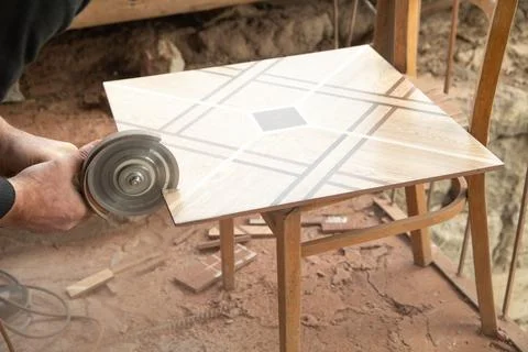 Worker cutting a ceramic tile with a grinder. Stock Photos