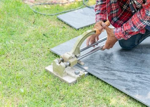 Worker cutting ceramic tile with manual tile cutter. Stock Photos