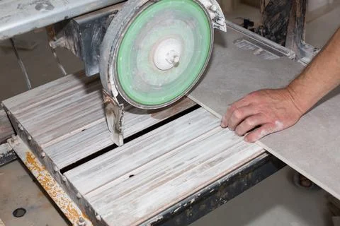A worker is cutting a ceramic tile on a special electric wet water cutter s.. Foto stock