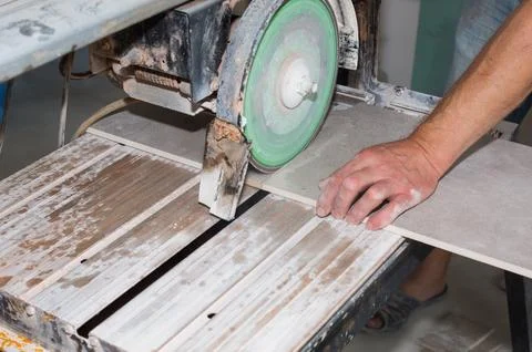 A worker is cutting a ceramic tile on a special electric wet water cutter s.. Stock Photos