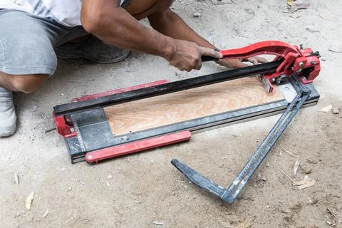 Worker cutting ceramic tile with tile cutter tool Stock Photos