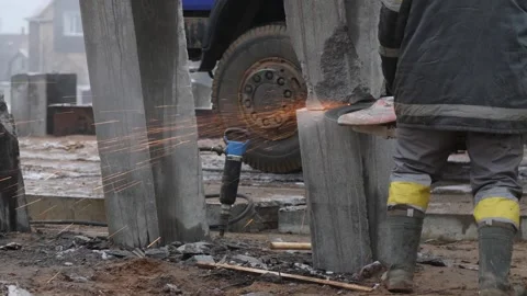 Worker cutting concrete piles with cutter or circular saw on construction site Stock Footage 158050511