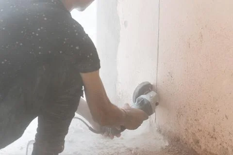 Worker cutting concrete wall with disc cutting tool, resulting dusk particles Stock Photos