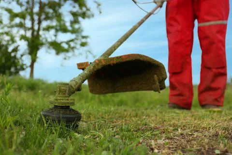 Worker cutting grass with string trimmer outdoors, closeup view Stock Photos