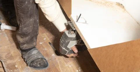 Worker cutting kitchen cabinet using electric saw. Stock Photos