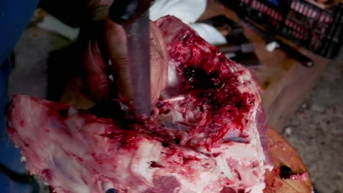 A worker cutting with a large knife the inner part of the skull of a pig Stock Footage 165539428