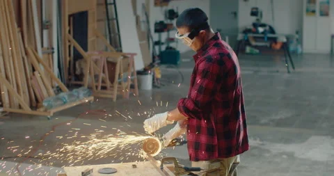 Worker cutting metal with an angle grinder in the workshop while wearing gloves Stock Footage 199624238
