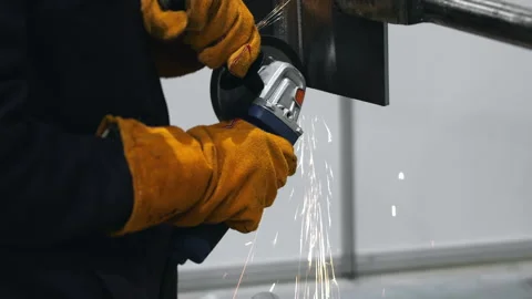 Worker cutting metal with angle grinder producing sparks in workshop. 스톡 동영상 347778722