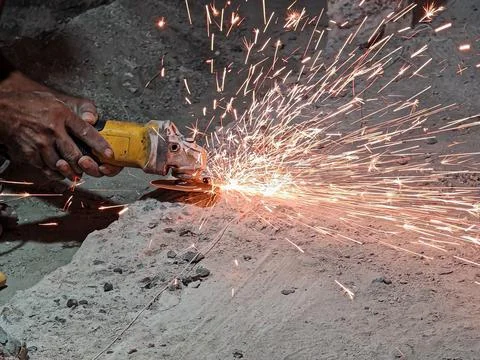 Worker cutting metal with angle grinder producing sparks during construction Stock Photos