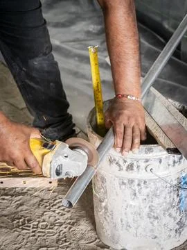 Worker cutting metal conduit with angle grinder Stock Photos