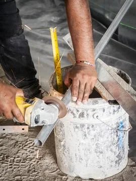 Worker cutting metal conduit with angle grinder Stock Photos