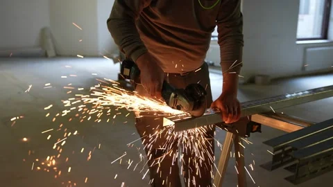 Worker cutting metal drywall studs with an angle grinder. Bright sparks flying Stock Footage 334267281