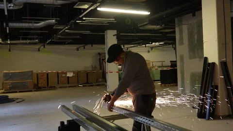 Worker cutting metal drywall studs with an angle grinder. Construction site Stock Footage 334267370