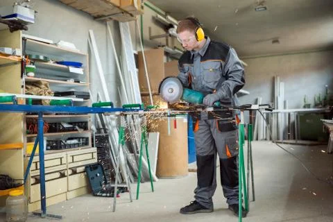 Worker cutting metal with grinder. Stock Photos
