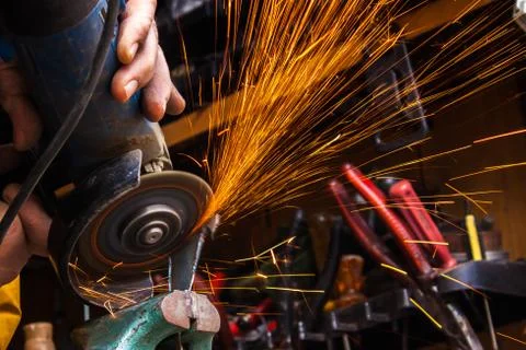 Worker cutting metal with grinder. Sparks while grinding iron. Selective low  Stock Photos