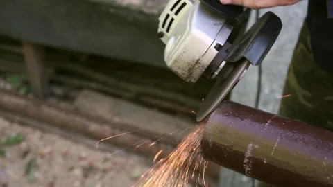 Worker cutting metal pipe with an angle grinder, producing bright sparks during Stock Footage 319029342