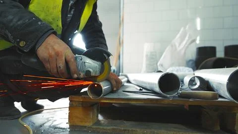 Worker Cutting Metal Pipe with Angle Grinder. A close-up shot of a worker using Stock Photos