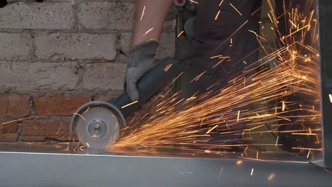 A worker cutting a metal sheet with an angle grinder tool in 4K slow motion Stock Footage 346307606