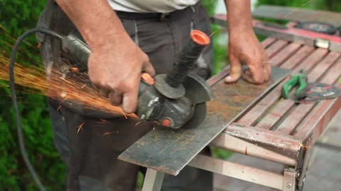 Worker cutting metal tube using an Angle Grinder. Bright sparks and flashes Stock Footage 258645514